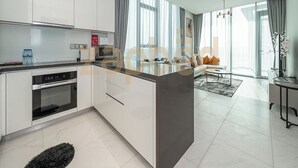 A modern kitchen with white cabinets, a built-in oven, and a large island. - Zapbed-1 BR in District One Residence 16 (Dubai)