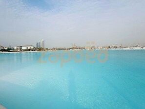 Ein großer, klarer, blauer Swimmingpool mit einer Stadtansicht im Hintergrund.