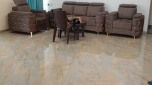 Ein Wohnzimmer mit braunem Sofa, passendem Sessel und Esstisch mit Stühlen.