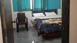 Ein Schlafzimmer mit einem Bett, einem Sessel und einem Fenster mit Vorhängen.