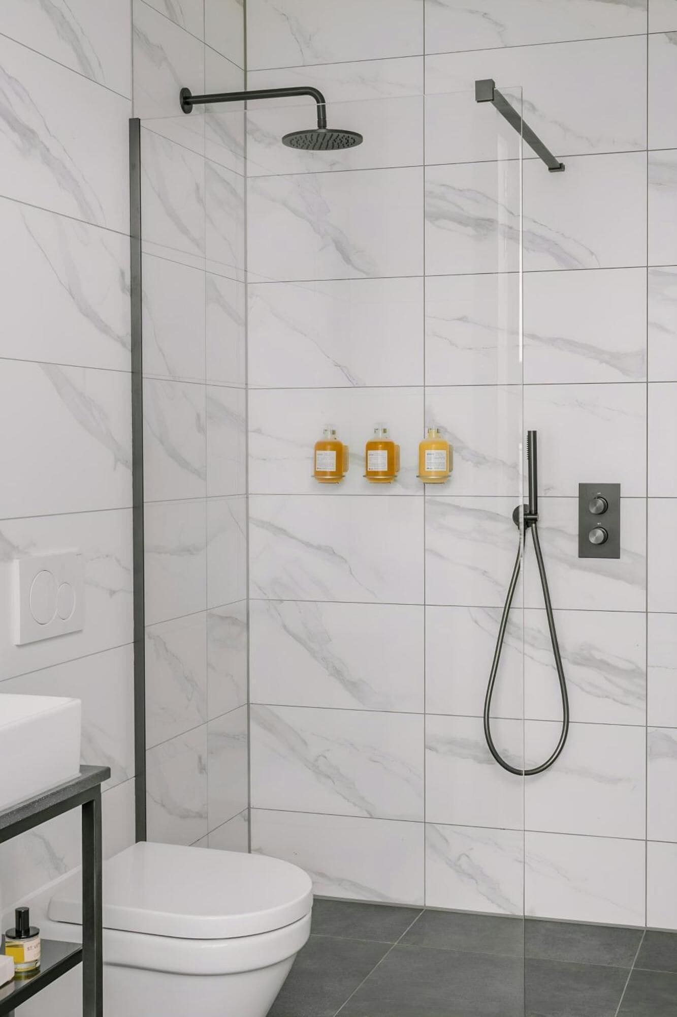 A modern bathroom with a white toilet, a sink, and a shower area.