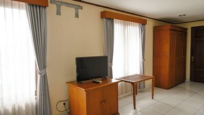 Una habitación con una televisión sobre un mueble de madera, una mesita y un armario.