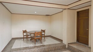 Una habitación con una mesa redonda de madera y cuatro sillas, una puerta de madera y un suelo de baldosas con un borde de mármol.