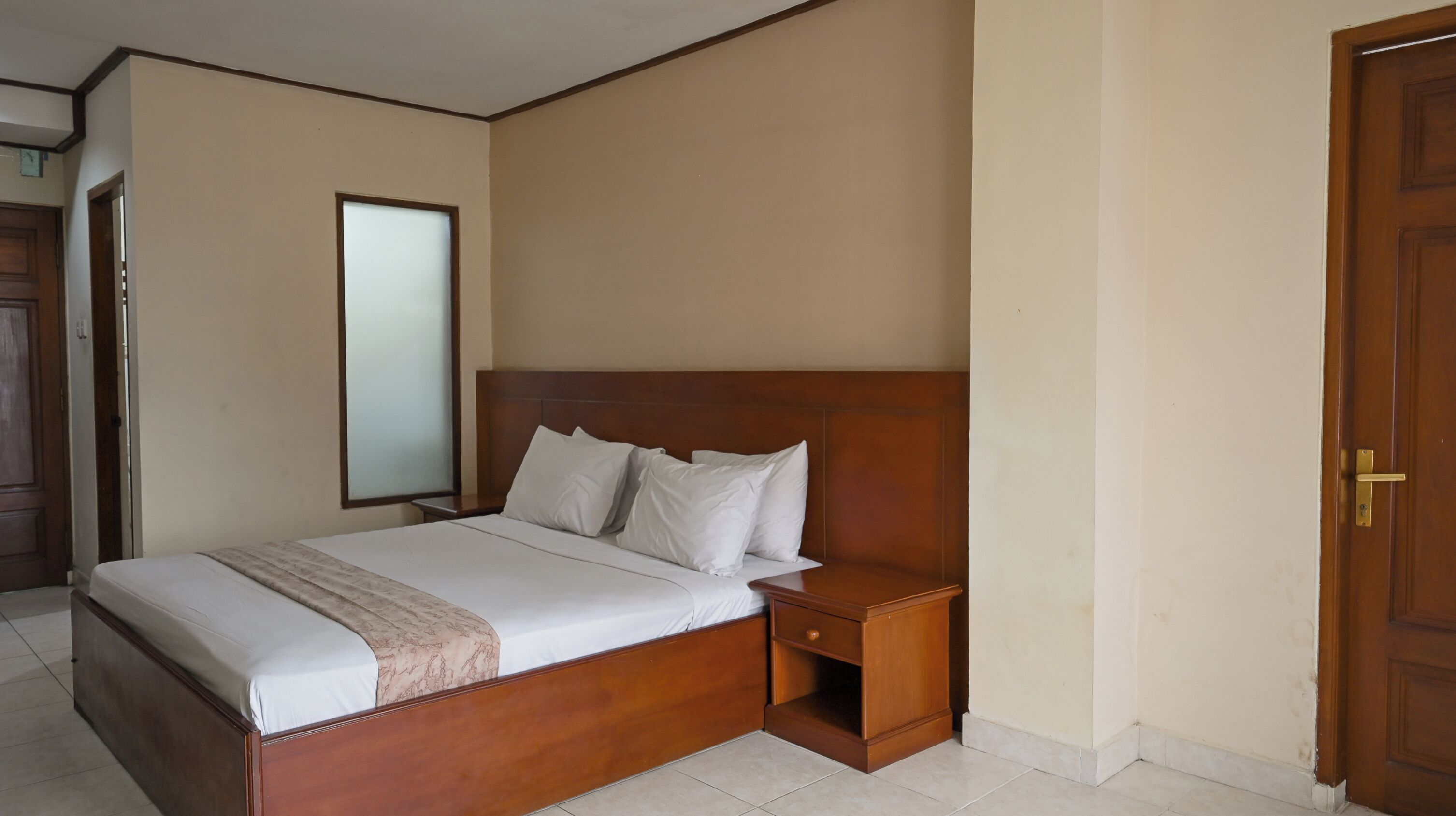 A neatly made bed with a wooden headboard, a bedside table, and a nightstand.