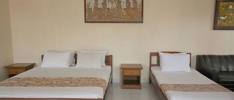 A hotel room with two beds, a wooden headboard, a nightstand, and a black leather couch.