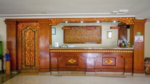 Un área de recepción con un mostrador de madera, una mesa de recepción y una obra de arte grande enmarcada arriba.