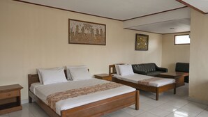 Una habitación de hotel con dos camas individuales, un sofá, una mesita y dos mesitas de noche.