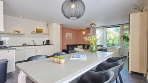 Uma cozinha moderna com armários brancos, uma mesa de jantar com cadeiras pretas e um vaso com flores.