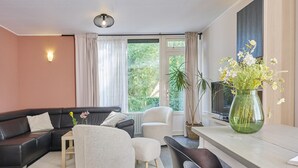 Uma sala de estar moderna com sofá, poltrona e mesa de jantar com cadeiras.