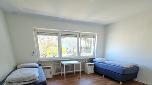 Une chambre avec deux lits, une petite table et un radiateur.