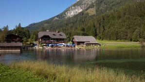 Een houten lodge aan een meer, met een steiger en een berg op de achtergrond.
