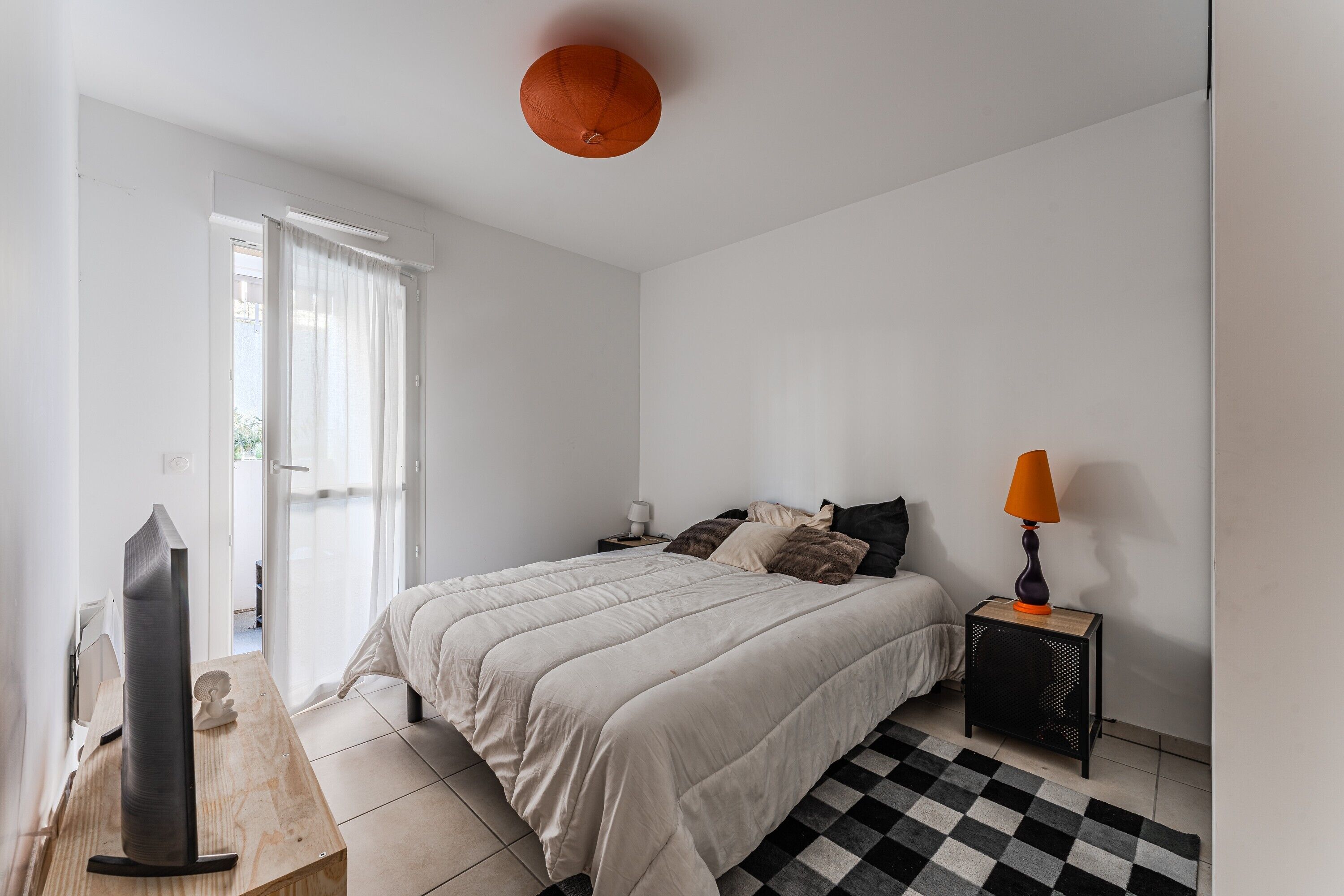 Ein Schlafzimmer mit einem Bett, einem Fernseher, einer Lampe und einem Schachbrettmuster-Teppich.
