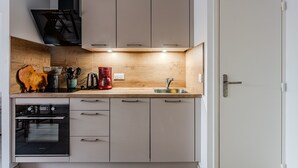 Een moderne keuken met een inbouwoven, een koffiezetapparaat en een houten spatwand.