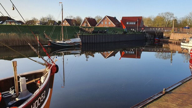 A calm harbor with boats docked, a wooden pier, and houses in the background. - Holiday Apartment Jana (Wangerland)