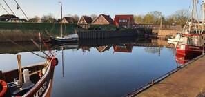 Een rustige haven met aangemeerde boten, een houten steiger en huizen op de achtergrond.