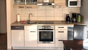 A modern kitchen with built-in appliances, a dishwasher, and a coffee maker. - Holiday Apartment Jana (Wangerland)