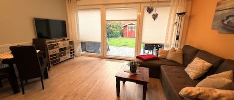Un salon comprenant un canapé, une table basse, un téléviseur et un meuble en bois.
