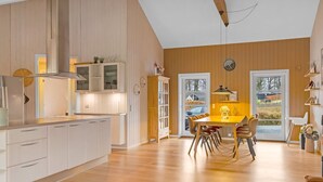 A modern kitchen with white cabinets, a dining area with a wooden table and chairs, and a large window with a view of the outside.