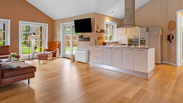 A modern kitchen with a central island, wooden flooring, and large windows.