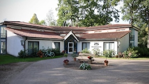 A two-story hotel with a red-tiled roof, a central entrance with a bench, and a bicycle parked outside. - Heidenauer Hotel im Park (Heidenau)
