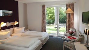 A hotel room with two beds, a desk, a chair, a TV, and a view of the outdoors. - Heidenauer Hotel im Park (Heidenau)