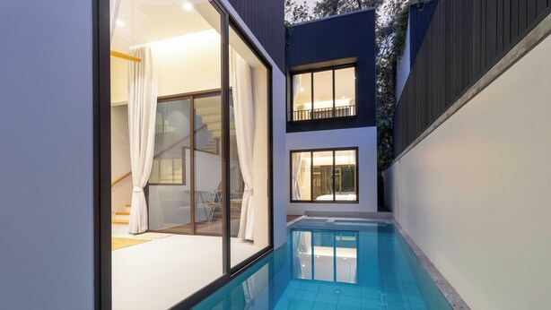 Ein modernes Haus mit Schwimmbad, großen Fenstern und einer Treppe, die zu einer oberen Ebene führt.