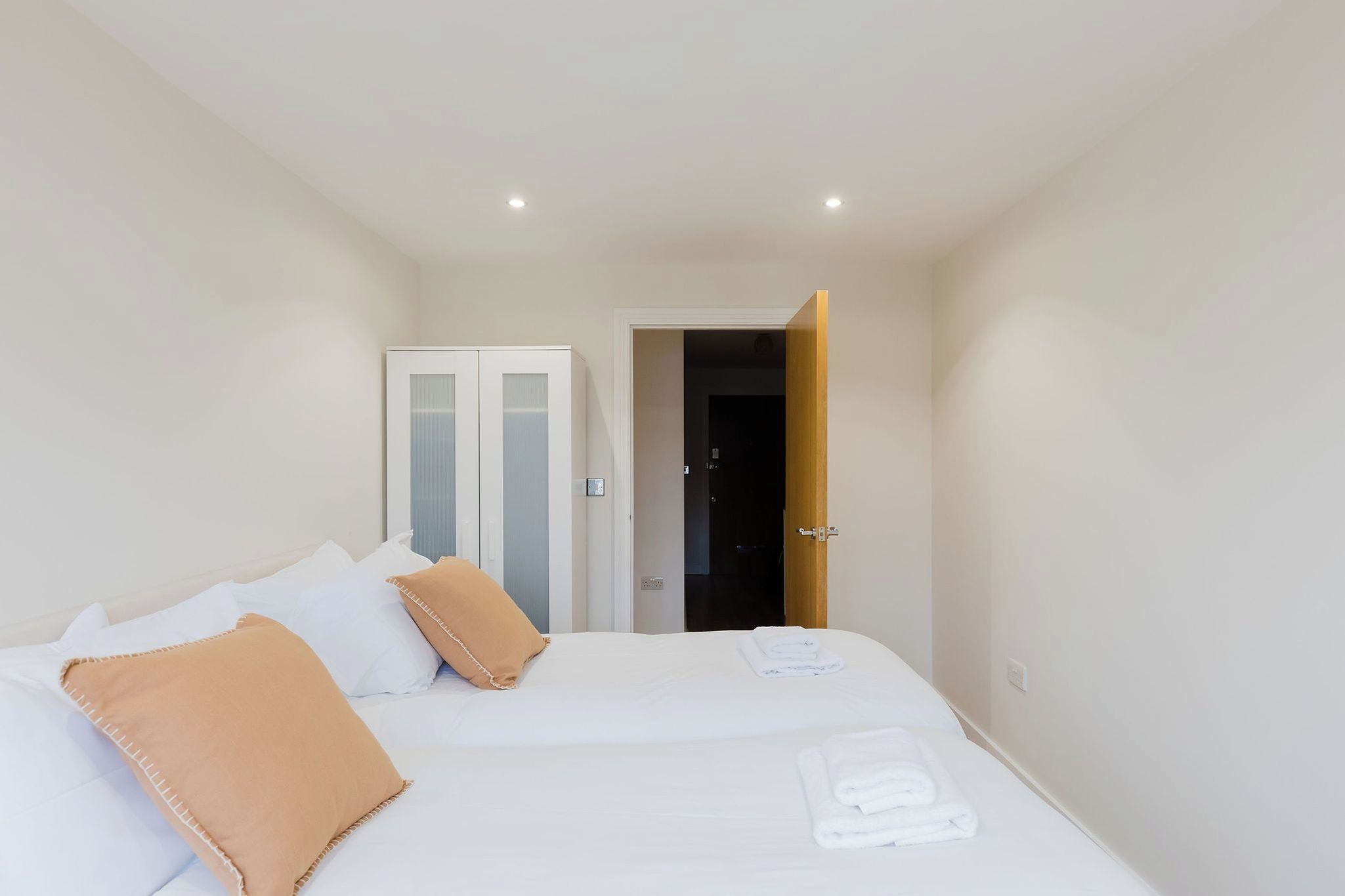 Une chambre à coucher avec un lit, des oreillers, une porte et un interrupteur.