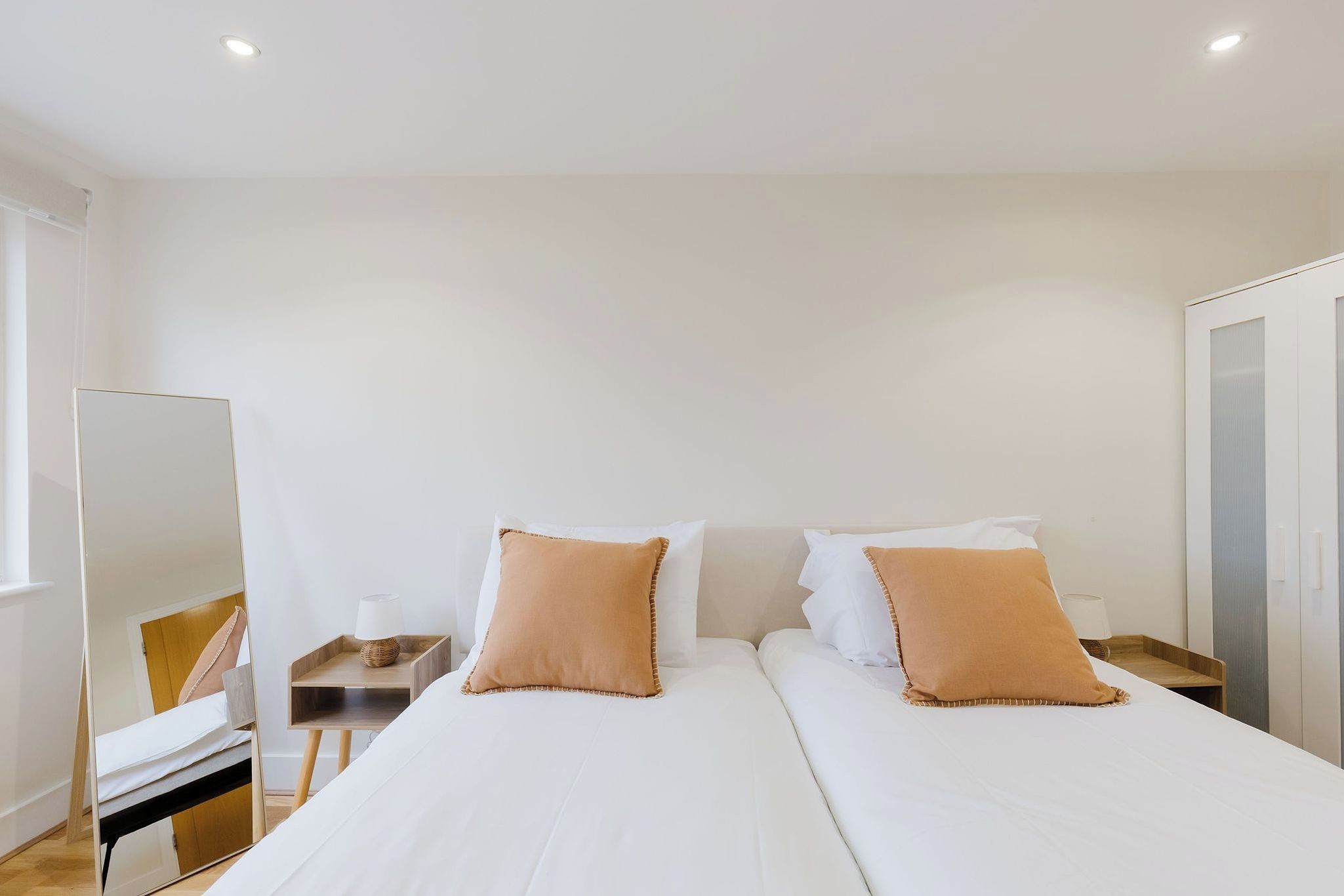 Quarto de hotel com uma cama grande, duas mesas de cabeceira, um espelho e um guarda-roupa.