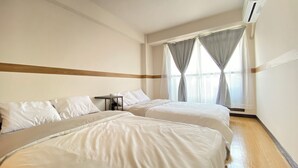 Una camera d'albergo con due letti, un tavolino e una finestra con tende.