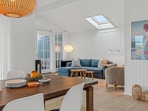 A modern living room with a blue sofa, a wooden dining table, and a skylight above. - "Odeta" - 50m from the sea by Interhome (Skagen)