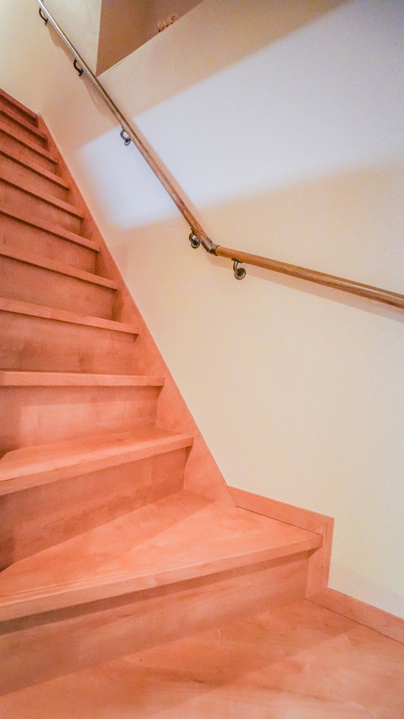 A wooden staircase with a handrail and a landing.