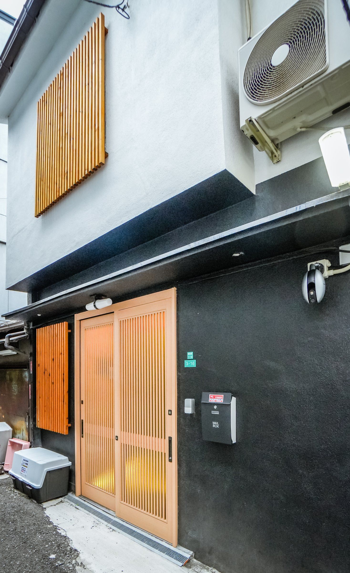 Un edificio con una puerta de madera grande, un buzón y una rejilla en la pared.