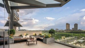 Un balcón moderno con techo de cristal, con vistas a un paisaje urbano de edificios altos.