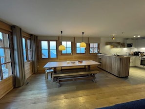 A modern kitchen with wooden cabinetry, a central island, and pendant lighting. - Les Planches de Villard 5* Chalet – Terrace, sauna – Alpe d’Huez area (Villard-Reculas)