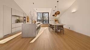 Een moderne keuken met een centraal eiland, barstoelen en een eethoek met een tafel en stoelen.