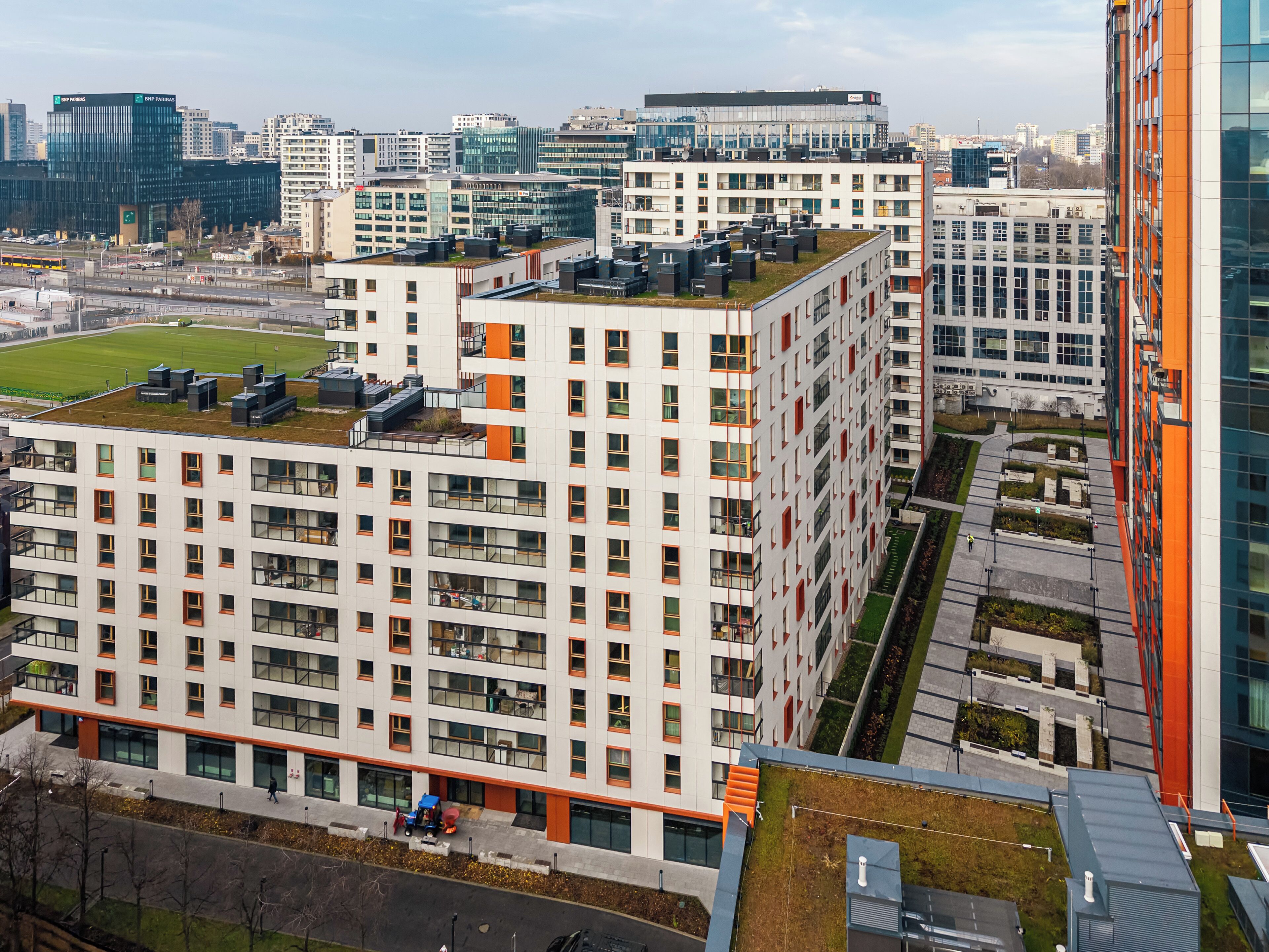 A high-rise building with multiple floors, large windows, and a rooftop garden.