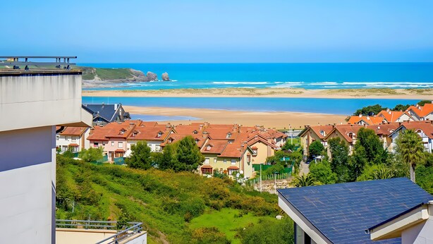 A coastal residential area with houses, a beach, and a clear sky. - Mymogrohome – Modern Apartment with Sea View Terrace in Mogro (Mogro)