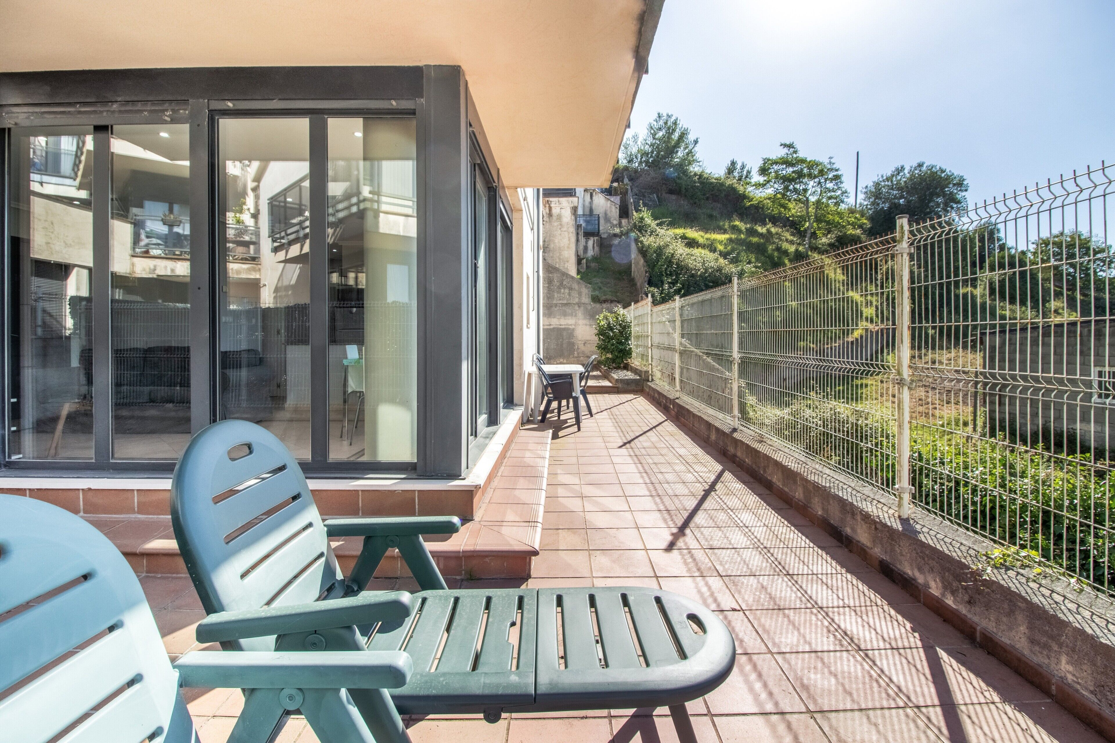 Un patio con mobiliario exterior, una entrada por puerta de vidrio y vistas a una colina.