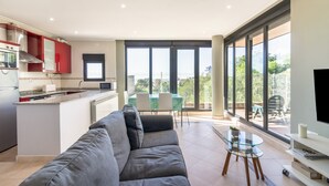 A modern living room with a grey sofa, a glass coffee table, and a TV stand. - Mymogrohome – Modern Apartment with Sea View Terrace in Mogro (Mogro)
