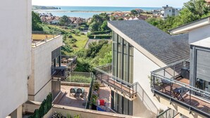 A modern building with a balcony overlooking a garden and a view of the sea. - Mymogrohome – Modern Apartment with Sea View Terrace in Mogro (Mogro)