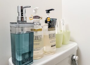 A bathroom shelf with various toiletries including a blue bottle, a white bottle, and a clear bottle with a pump. - meisei ebiyaminami (Osaka)