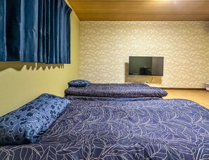 A bedroom with a bed, pillows, a television, and a patterned wall. - meisei ebiyaminami (Osaka)