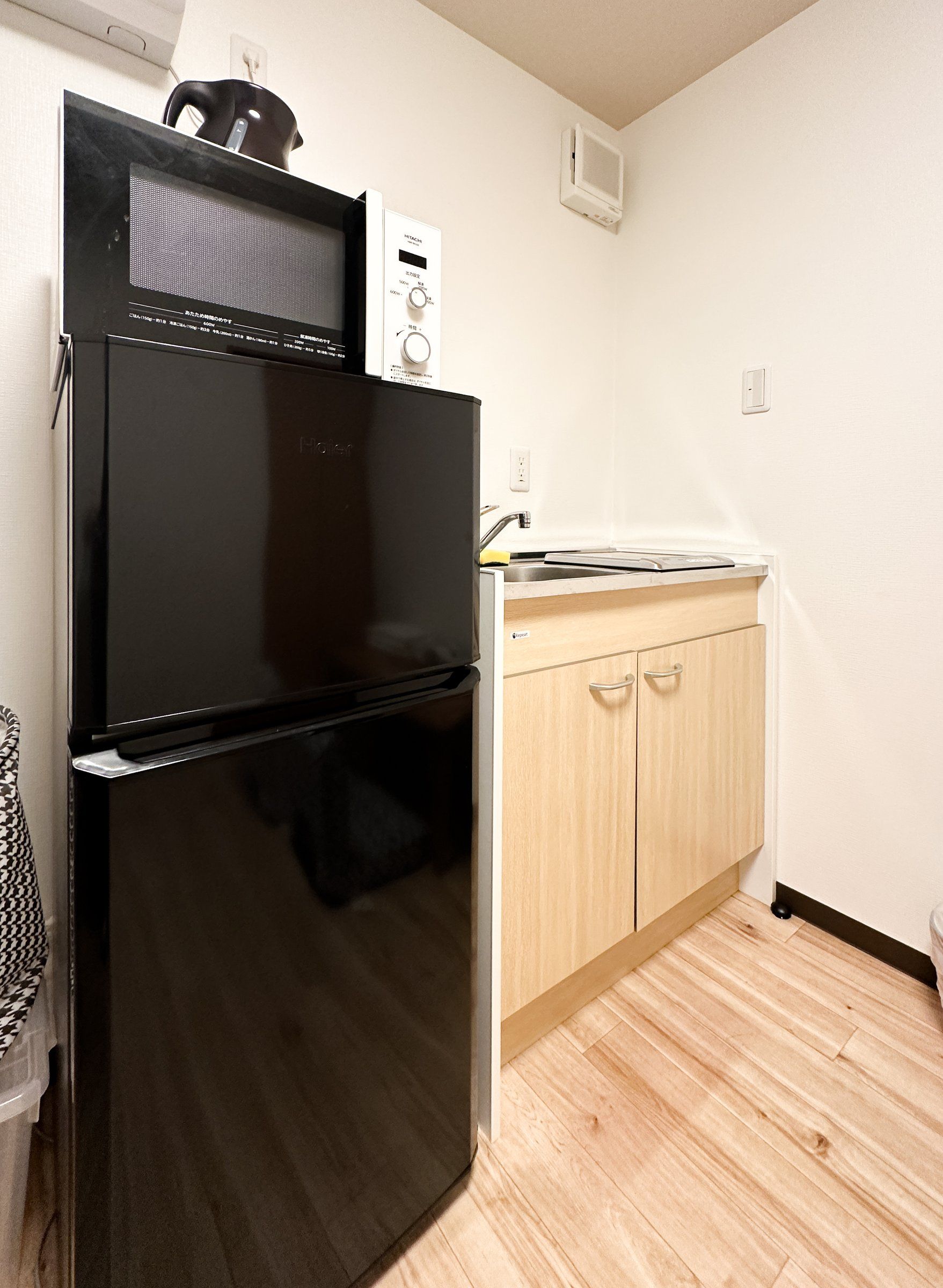 A compact kitchen with a black refrigerator, a microwave, and a wooden cabinet.