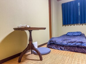 A room with a bed, a table, and a window with curtains. - meisei ebiyaminami (Osaka)