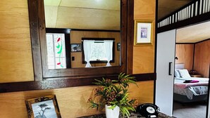 A rustic wooden cabinet with drawers, a potted plant, and a framed picture. - Cosy retro renovated cottage with mountain setting out back (Queenstown)