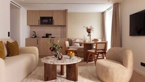 A modern living room with a sofa, a round coffee table, and a dining area with a table and chairs. - Superb air-conditioned apartment - Le Marais (Paris)