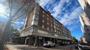 A multi-story building with a ground-level entrance, a bicycle parking area, and a parking lot with several cars. - M9 REST HOUSE VENICE (Mestre)