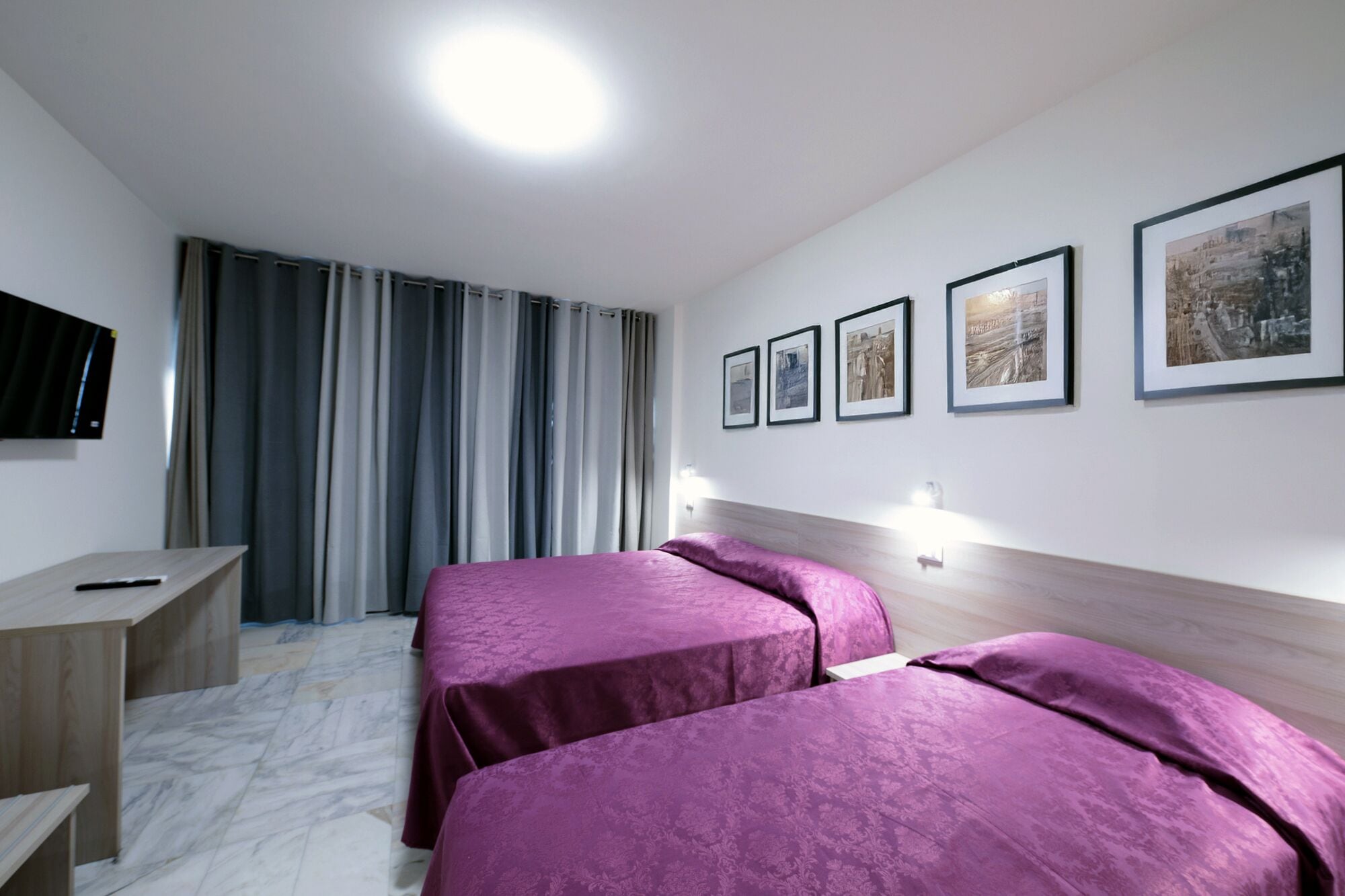 A hotel room with two beds, a desk, and a TV.