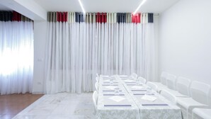 A conference room with a long table, white chairs, and a curtain with a color stripe pattern. - M9 REST HOUSE VENICE (Mestre)