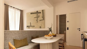 A modern living room with a grey sofa, a round coffee table, and a minimalist abstract painting on the wall. - Elegant apartment with AC - Le Marais (Paris)